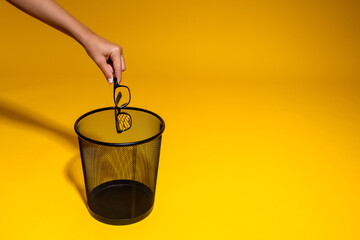 The hand throws black glasses into the trash. The glasses are thrown into the office wastebasket....