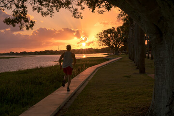 Young man running in a beautiful sunset by the lake. Sport concept