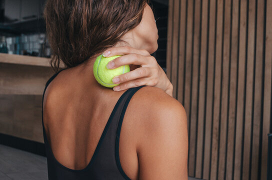 Woman doing self-massage with tennis ball.  Myofascial release