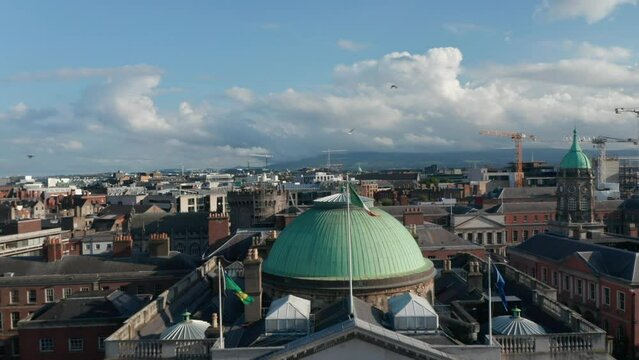 Pull back footage of City Hall. Historic building with green dome and national flag. Revealing buildings on waterfront. Dublin, Ireland