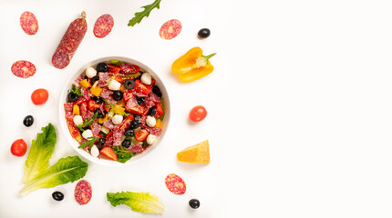 Salad with tomato, olives, bell pepper, salami, mozzarella, lettuce and arugula on white background. Top view, concept for menu or ingridient