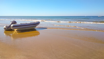 Fototapeta premium Rubber inflatable boat on the sandy shore of the sea on a sunny day