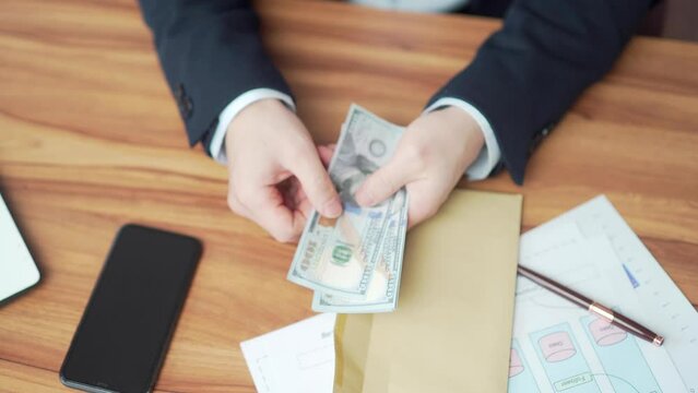 businessman hands counting money pulling out of envelope at desk in office desktop. Business man banker counts banknotes financial salary bribe holding cash in dollars at workplace. top view close up