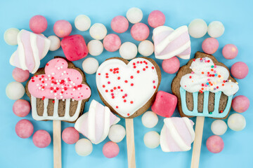 banner cookies on a stick and candy on a blue background. Delicious sweets top view and copy space....