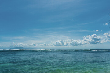 The beautiful horizontal line of seascape meets the blue sky with nice clouds on a sunny day.