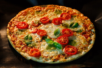Vegetarian crusty pizza with mozzarella, cherry tomatoes, pesto sauce and basil leaves cook in oven