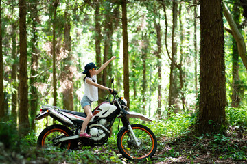 Fototapeta na wymiar 山道でオフロードバイクに跨る少女