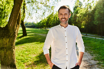 Portrait of smiling mid adult man standing at park during summer afternoon