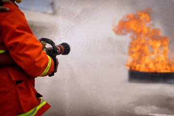 In to the fire,Brave firefighter using extinguisher and water from hose for fire fighting, ...