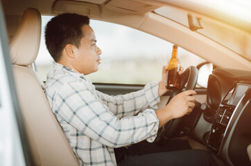 Drunk man holding bottle of beer while driving a car, campaigning for drunken not driving avoiding accidents on road, Don't drink and drive concept.