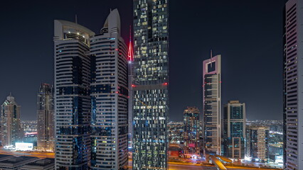 Panorama showing aerial view of Dubai International Financial District with many skyscrapers night timelapse.