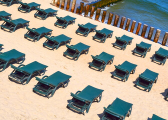 Rows of free green sun loungers on an empty sandy beach. Closed Vacation Concept or low season