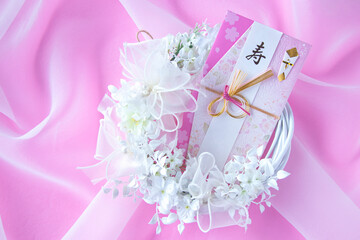 ウェディングイメージ　白い花の白いリースと結婚祝いの熨斗袋（オーガンジー。ピンクバック）