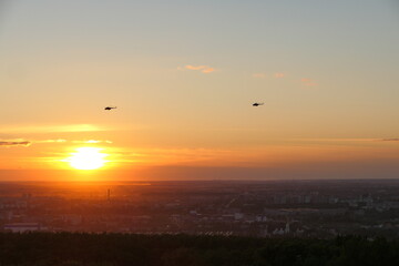 Fototapeta premium Two helicopters in the sky against the backdrop of the setting sun, Bright sunset. High quality photo