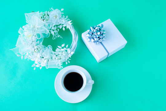 ウェディングイメージ　白い花の白いリースとコーヒーと銀色リボンの白いプレゼント（グリーンバック）