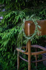 wild meadow flower wreath in the summer garden on the edge of a wooden chair. Summer solstice day,...
