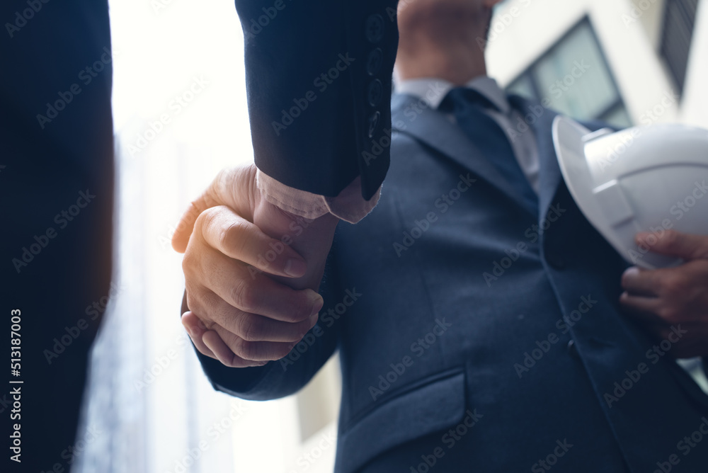 Wall mural two civil engineer or architect holding helmet and handshaking at construction site after mega proje