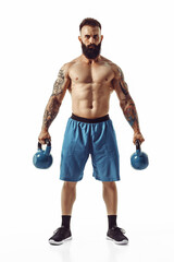 Muscular shirtless tattooed bearded male athlete bodybuilder workout with kettlebell on a white background. Isolate - obrazy, fototapety, plakaty