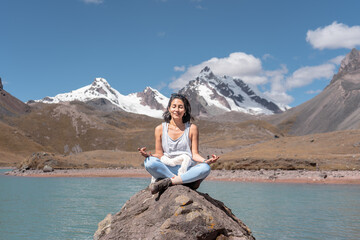 Mujer latina meditando en las montañas del Perú, realizando una pose en yoga.
