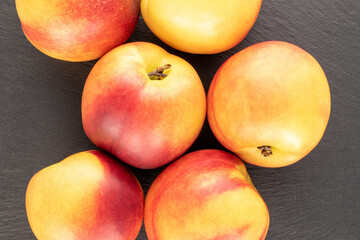 Several ripe juicy nectarines on a slate stone, close-up, top view.
