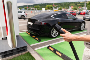 Man holding plug of electric car charging station	
