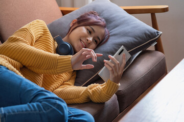 Obraz premium relax, de-stress, holiday, happy, Asian woman relaxing at home listening to music from smartphone and laptop happily.