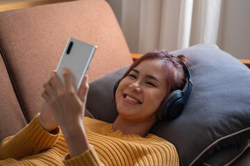 relax, de-stress, holiday, happy, Asian woman relaxing at home listening to music from smartphone and laptop happily.
