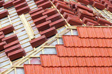 Roofing construction with clay roof tiles. Roofer laying ceramic roof tiles. Lay roof tiles