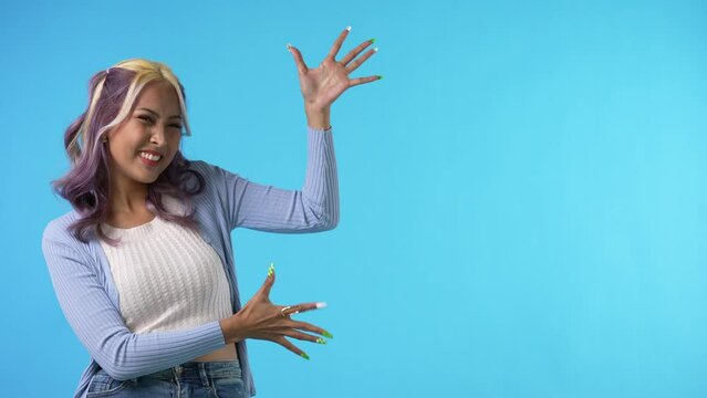 Young asian woman showing empty copy space on the open hands palm for text or product isolated on blue background