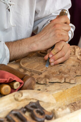 Carpenter craftsman carving wooden shield by hand with chisel