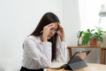 Asian woman hold the head with headaches from work burdens and debts.