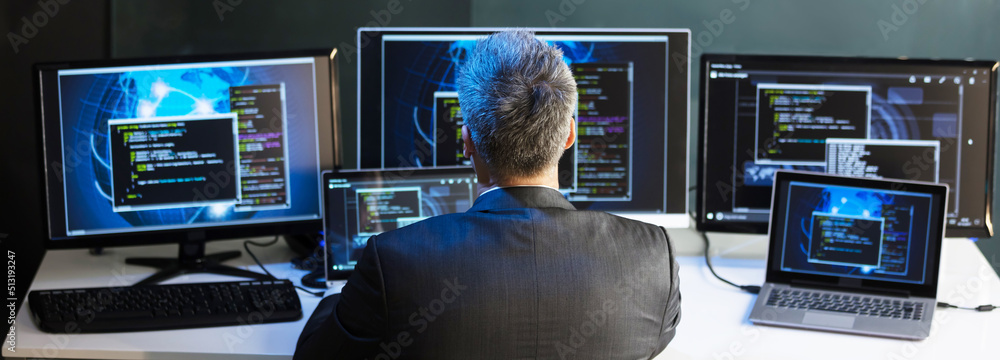 Poster businessman looking at multiple computer screens