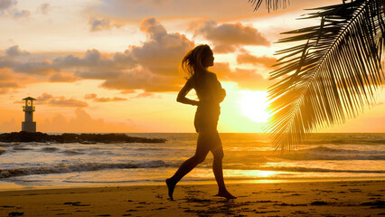 Young woman exercising running barefoot on sea beach with sunset ocean background. Female athlete...