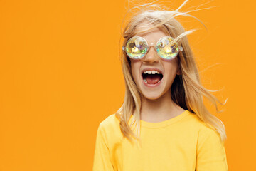 funny, playful girl posing standing on a bright background in yellow clothes and shiny, carnival...