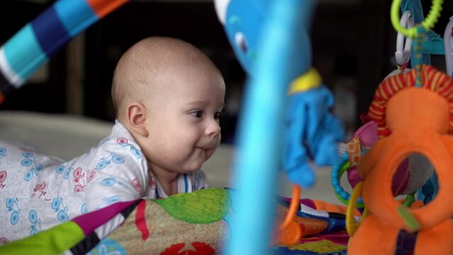 Newborn Active Baby Cute Smiling Teethless Face Portrait Early Days On Stomach Developing Neck Control. 5 Months Child In Playpen Gnaws Toys Look At Camera. Infant, Childbirth, Beginning Concept