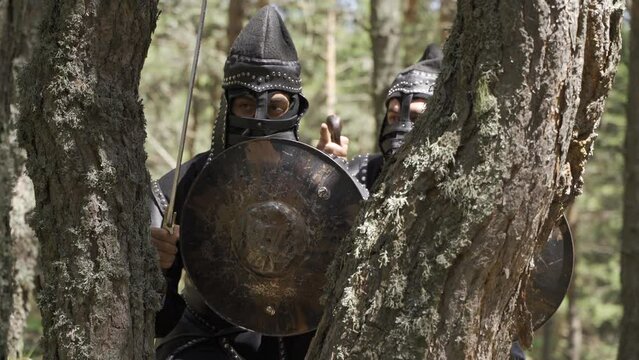 Mongolian empire soldiers.
Two soldiers observing in the forest. Soldiers in black period suits strategize under a tree. Historical reenactment.
