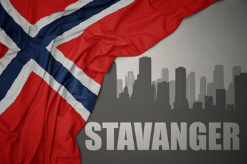 Fototapeta na wymiar abstract silhouette of the city with text Stavanger near waving national flag of norway on a gray background.