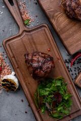 Large grilled Filet Mignon steak with butter and thyme served on a wooden board. Roast meat dish, close up