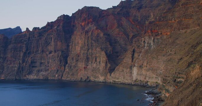 Los Gigantes cliffs. Sunset on Tenerife, Canary Islands, Spain. The view of the mountains opens gradually, the frame appears horizontally. Hend held footage.