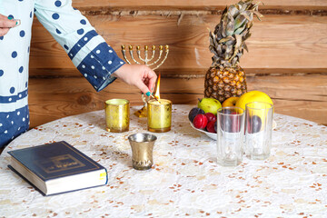 Fototapeta na wymiar Jewish religious woman lights Shabbat candles at the table.