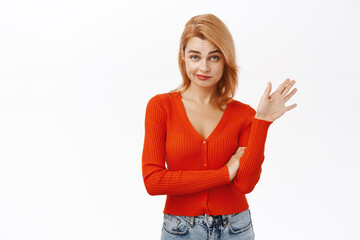 Image of reluctant young woman wave away hand to decline, reject smth uninteresting, smirk with skeptical face expression, standing over white background