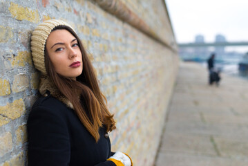 Portrait of beautiful young sad woman standing on the city street in the autumn