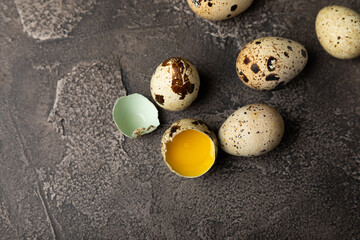 Quail eggs on a black texture background. Whole and broken quail eggs. Natural products. Place for text. Fresh quail eggs.