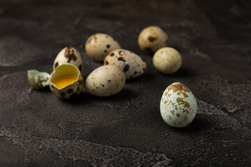Quail eggs on a black texture background. Whole and broken quail eggs. Natural products. Place for...