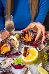 Closeup of a dish of sea urchins with ice in a plate and cutlery on a wooden table with selective focus
