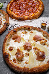 three different kinds of pizzas, around and heart shaped on white background with copy space, salami, mushrooms, tomaton, pepperoni, cherry tomato and cheese.