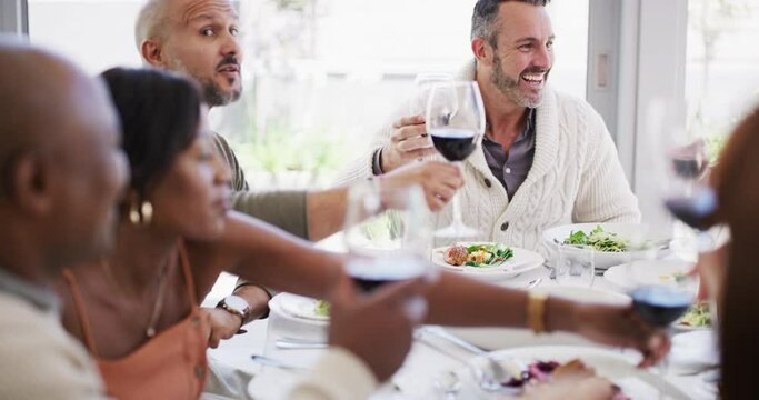 Closeup of a group of diverse friends having a lunch party at a restaurant and sharing a toast with red wine. Colleagues having food and celebrating occasion with an alcoholic beverage at home
