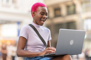 Happy african woman using the laptop on the street