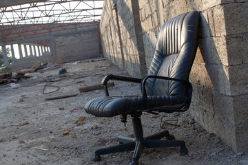 Empty black chair against dirty grunge brick wall background