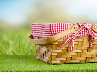 Obraz premium A beautiful picnic basket on a bright green grass against the backdrop of nature. Summer vacation, picnic. Beautiful nature, delicious organic food. Banner, advertisement, invitation.